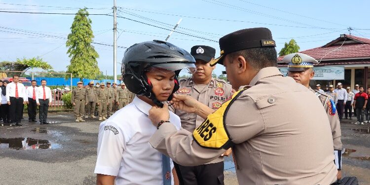 FOTO: MATAKALTENG - Kapolres Barsel AKBP Asep Bangbang Saputra memasang helm secara simbolis kepada salah satu pelajar, pada apel Operasi Keselamatan Telabang Tahun 2024.