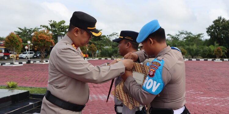 FOTO : HUMAS POLRES GUMAS/MATA KALTENG - Kapolres Gumas AKBP Theodorus Priyo Santosa ketika menyematkan pita kepada perwakilan peserta apel gelar pasukan operasi keselamatan telabang 2024 dan pencanangan aksi kejahatan, Senin, 4 Maret 2024.