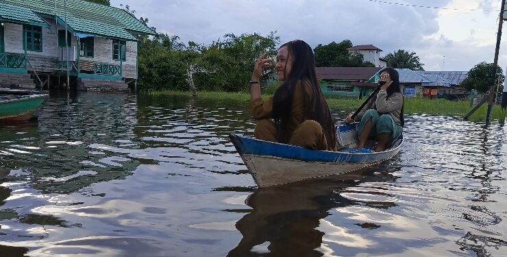 FOTO : DEVIANA/MATAKALTENG - Aktivitas warga di Desa Hanjalipan saat tergenang banjir menggunakan perahu, belum lama ini.