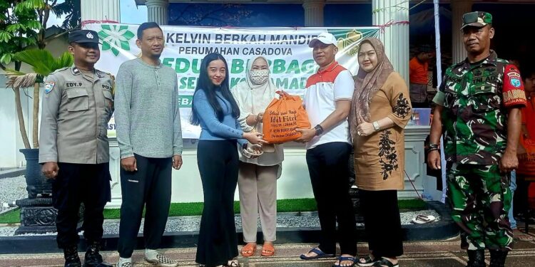 FOTO: RZL/MATAKALTENG - Pemilik PT Kelvin Berkah Mandiri, Sahrin (topi putih), saat menyerahkan paket sembako kepada salah seorang masyarakat didampingi oleh Lurah Panarung, Evi Kahayanti.