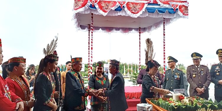 FOTO : SID/MATA KALTENG - Ketua DPRD Kabupaten Gumas Akerman Sahidar ketika menerima potongan tumpeng dari Pj Bupati Herson B. Aden, usai upacara peringatan hari jadi ke-22 Kabupaten Gumas, Jumat 21 Juni 2024.