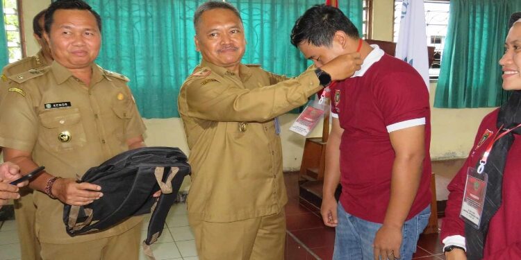FOTO: IST/MATAKALTENG - Kepala Disnakertrans Prov. Kalteng Farid Wajdi secara simbolis mengalungkan tanda peserta Pelatihan Perluasan Kesempatan Kerja DBH DR.