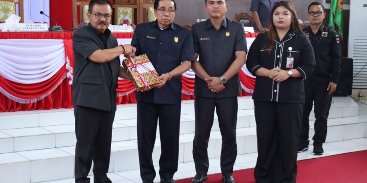 FOTO : DISKOMINFO SANTIK/MATA KALTENG - Pj Bupati Gumas Herson B Aden ketika menyerahkan dokumen nota keuangan tentang Raperda Perubahan APBD tahun 2024 kepada Ketua DPRD Akerman Sahidar, pada rapat paripurna ke-9 masa persidangan III tahun sidang 2024, Senin, 29 Juli 2024.
