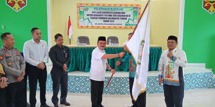 FOTO : DISKOMINFO SANTIK/MATA KALTENG - Pj Bupati Gumas Herson B Aden ketika menyerahkan bendera LAQSI kepada Ketua LASQI Nusantara Jaya Jhonson Ahmad, dalam kegiatan pelepasan kafilah yang akan mengikuti FSQ tingkat provinsi, di aula kantor kemenag setempat, Rabu, 31 Juli 2024.