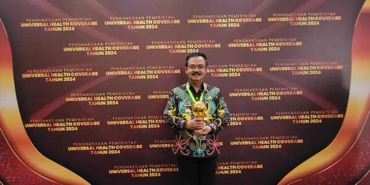 FOTO : DISKOMINFO SANTIK/MATA KALTENG - Pj Bupati Gumas Herson B Aden saat menunjukkan penghargaan UHC, pekan lalu.