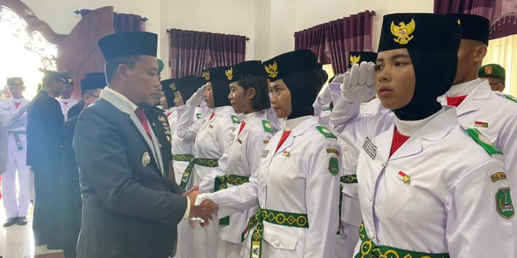 Foto : AKH/MATAKALTENG - Pj Bupati Sukamara Rendy Lesmana saat memberikan ucapan selamat kepada satu persatu anggota paskibraka yang baru di kukuhkan.