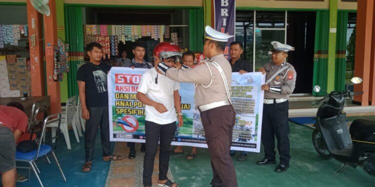 FOTO: MATAKALTENG - Personel Satlantas Polresta Palangka Raya, pada saat memberikan contoh cara menggunakan helm yang benar kepada salah seorang warga.