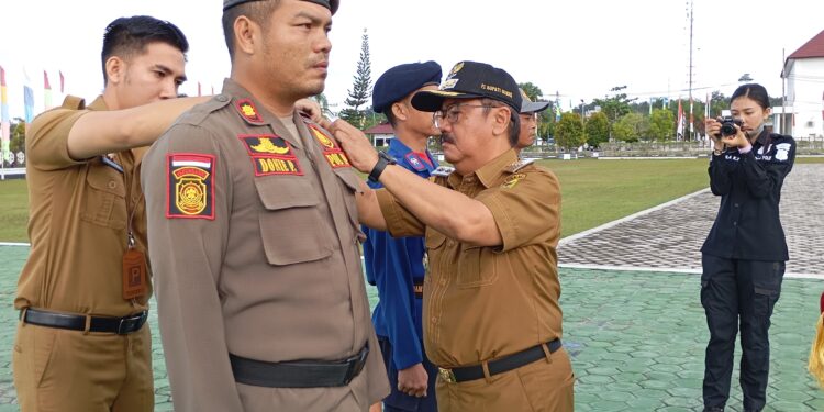 FOTO : DISKOMINFO SANTIK/MATA KALTENG - Pj Bupati Gumas Herson B Aden ketika menyematkan pita kepada perwakilan peserta apel gelar pasukan operasi praja wibawa dan operasi mantap praja telabang, di halaman kantor bupati setempat, Senin, 26 Agustus 2024.