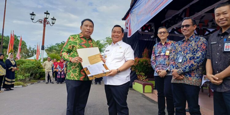 FOTO ; DEVIANA/MATAKALTENG - Bupati Kotim Halikinnor saat menyerahkan SK purna tugas kepada Fajrurrahman, Jumat 30 Agustus 2024.