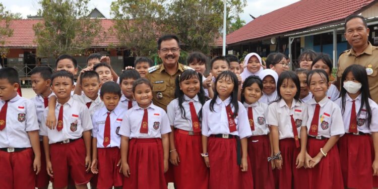 FOTO : DISKOMINFO SANTIK/MATA KALTENG - Pj Bupati Gumas Herson B Aden ketika berfoto bersama dengan peserta didik di SDN 1 Kurun, belum lama ini.