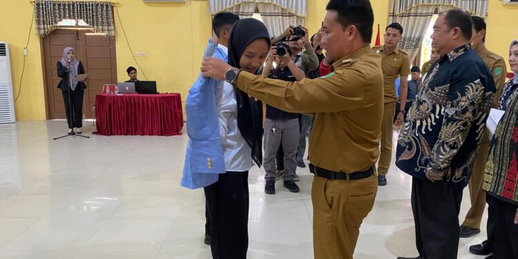 Foto : AKH/MATA KALTENG - Pj Bupati Sukamara Rendy Lesmana saat memasangkan almamater kepada mahasiswa baru saat pembukaan PKKMB SPDKU Polnep Sukamara.