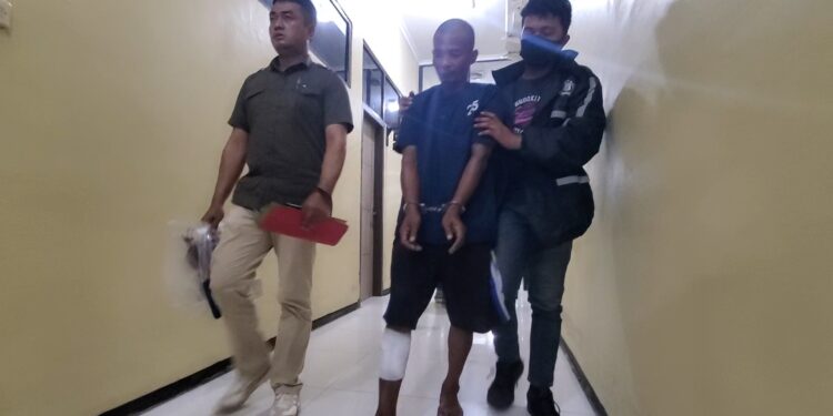 FOTO: AGUS/MATAKALTENG– SN, pelaku begal di Wengga, saat digiring aparat kepolisian mengenakan baju tahanan berwarna biru.