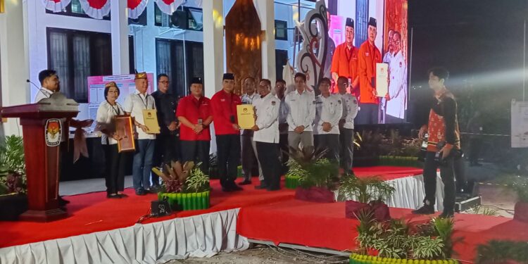 FOTO : KPU GUMAS/MATA KALTENG - Ketua KPU Kabupaten Gumas Elfrinst G Tumon didampingi komisioner KPU, menyerahkan berita acara penetapan nomor urut paslon bupati dan wakil bupati gumas pada pilkada serentak, di halaman kantor KPU setempat, Senin, 23 September 2024 malam.