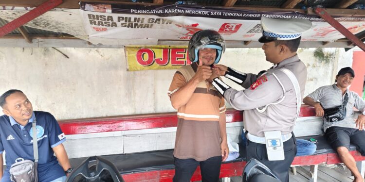 FOTO: MATAKALTENG - Personel Satlantas Polresta Palangka Raya, pada saat memasangkan helm SNI kepada salah seorang pengendara.