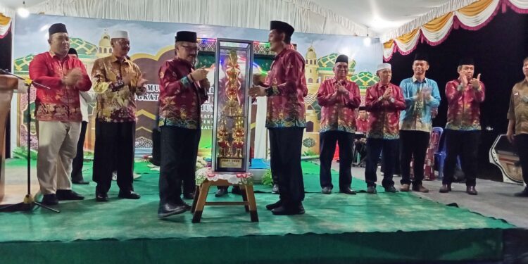 FOTO : DISKOMINFO SANTIK/MATA KALTENG - Pj Bupati Gumas Herson B Aden menyerahkan piala juara umum MTQ kepada Ketua LPTQ Jhonson Ahmad, untuk diperebutkan dalam MTQ XVII tingkat kabupaten tahun 2024, di Lapangan Baras Ngahai, Kelurahan Jakatan Raya, Kecamatan Rungan, Rabu, 23 Oktober 2024 malam.