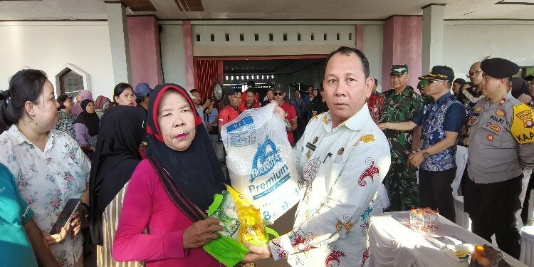 FOTO: IST/MATAKALTENG - Pj Bupati Katingan Sutoyo, saat menyerahkan paket sembako pasar murah kepada masyarakat, di halaman gedung sport Center Kota Kasongan.