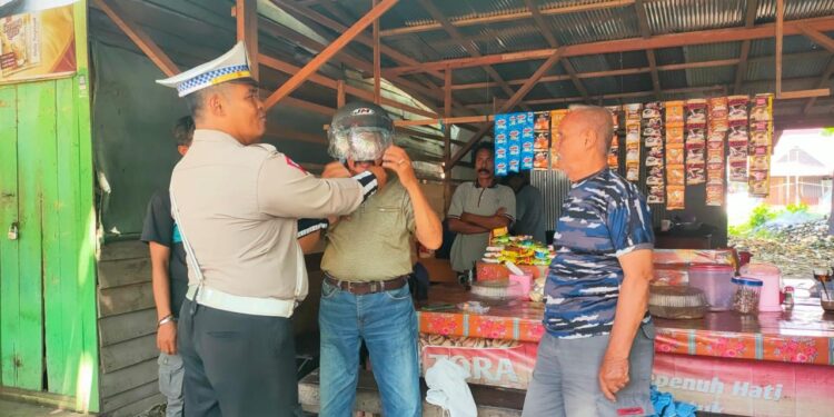 FOTO: MATAKALTENG - Personel Satlantas Polresta Palangka Raya pada saat memasangkan helm kepada salah seorang warga.