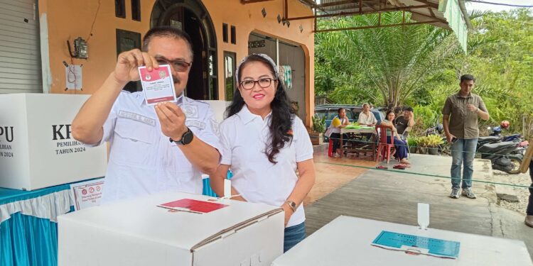 FOTO : DISKOMINFO SANTIK/MATA KALTENG - Pj Bupati Gumas Herson B Aden bersama istri ketika menunjukkan surat suara yang sudah dicoblos, di TPS 06, Kelurahan Tampang Tumbang Anjir, Kecamatan Kurun, Rabu (27/11).