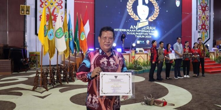 FOTO: Diskominfo Gumas/MATAKALTENG - Staf Ahli Bupati Guanhin ketika menerima penghargaan peringkat II menuju informatif dalam keterbukaan informasi badan publik tahun 2024, Rabu 4 Desember 2024 lalu.