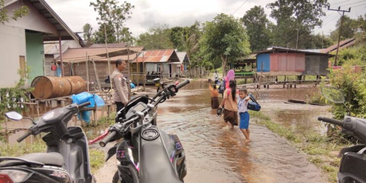 FOTO: MATAKALTENG - Personel Polsek Bukit Batu pada saat mengimbau waspada banjir ke anak-anak.