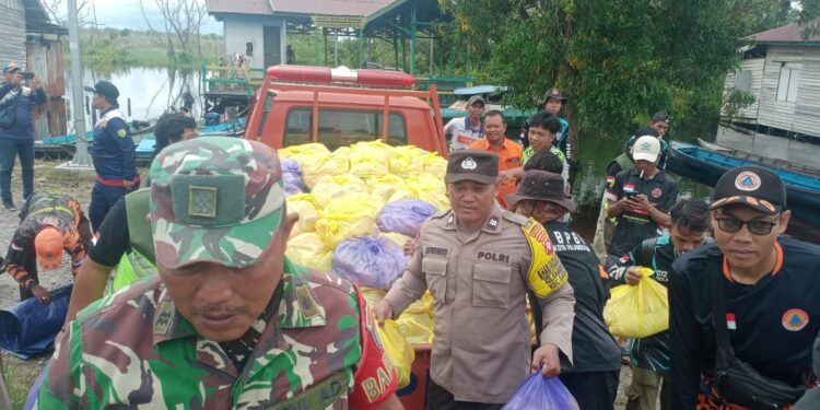 FOTO: MATAKALTENG - Personel Polsek Sabangau, pada saat menyalurkan bantuan sosial kepada korban banjir.