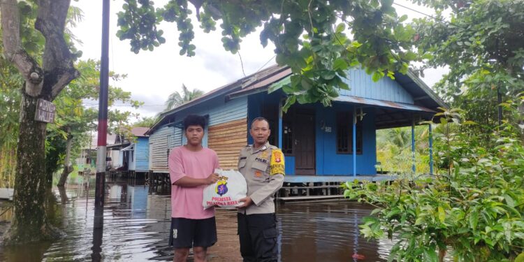 FOTO: MATAKALTENG - Bhabinkamtibmas Kelurahan Tanjung Pinang, Bripka Nur Rohim, pada saat memberikan bantuan sosial kepada warga terdampak banjir.