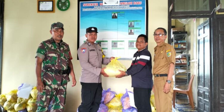 FOTO: MATAKALTENG - Personel Polsek Sabangau, pada saat meyalurkan sembako kepada warga.