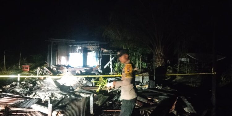 FOTO : POLSEK RUNGAN/MATA KALTENG - Personel Polsek Rungan memasang garis polisi di lokasi kebakaran rumah, di Desa Bereng Baru, Kecamatan Rungan, Kamis, 9 Januari 2025 malam.