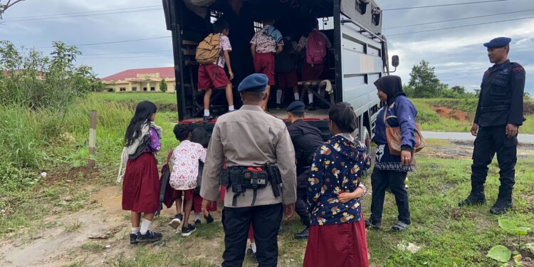 FOTO: MATAKALTENG - Personel Brimob Polda Kalteng pada saat membantu mengantarkan siswa ke sekolah.