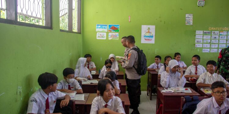 FOTO: MATAKALTENG - Personel Polresta Palangka Raya, pada saat membagikan Maka Bergizi Gratis kepada siswa SDN 6 Bukit Tunggal.