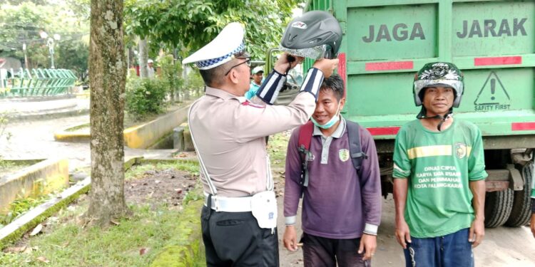 FOTO: MATAKALTENG - Personel Satlantas Polresta Palangka Raya, pada saat hendak memasangkan helm SNI gratis kepada petugas penyapu jalan.
