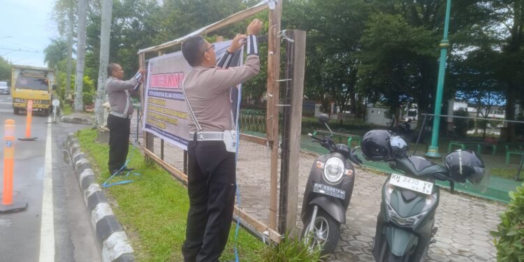 FOTO: MATAKALTENG - Personel Satlantas Polresta Palangka Raya, pada saat memasang spanduk imbauan.