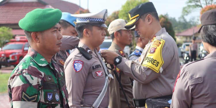 FOTO : HUMAS GUMAS/MATA KALTENG - Kapolres Gumas AKBP Theodorus Priyo Santosa menyematkan pita kepada perwakilan apel gelar pasukan operasi keselamatan telabang 2025, di halaman mapolres setempat, Senin, 10 Februari 2025.