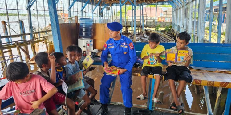 FOTO: MATAKALTENG - Personel Ditpolairud Polda Kalteng pada saat menemani siswa SD di Kapuas membaca.
