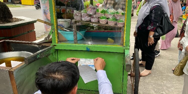 FOTO: IST/MATA KALTENG - Petugas BBPOM Kalteng saat menempel stiker tanda aman dikonsumsi pada gerobak pedagang takjil di Kota Sampit.