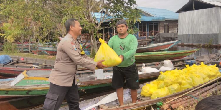 FOTO: MATAKALTENG - Bhabinkamtibmas Kelurahan Marang, Aipda Priyo Waluyo, pada saat menyalurkan bantuan sembako kepada korban banjir.