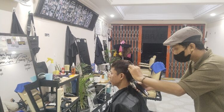 FOTO: AGUS/MATAKALTENG - Amin saat mencukur rambut pelanggan di Barbershop miliknya. 