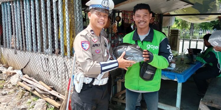 FOTO: MATAKALTENG - Personel Satlantas Polresta Palangka Raya, pada saat memberikan helm kepada pengendara ojol.