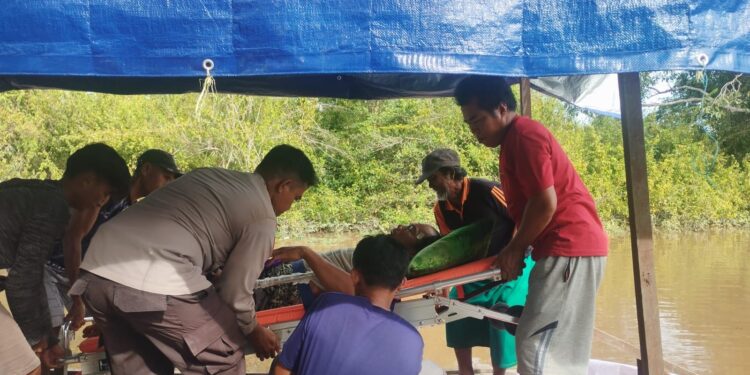 FOTO: MATAKALTENG - Bhabinkamtibmas Kelurahan Bereng Bengkel pada saat membantu mengevakuasi warga yang sakit dari kebanjiran.