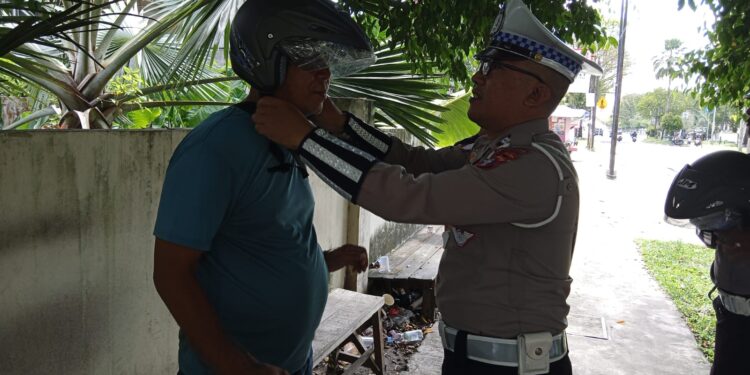 FOTO: MATAKALTENG - Personel Satlantas Polresta Palangka Raya, pada saat memasangkan helm kepada warga.