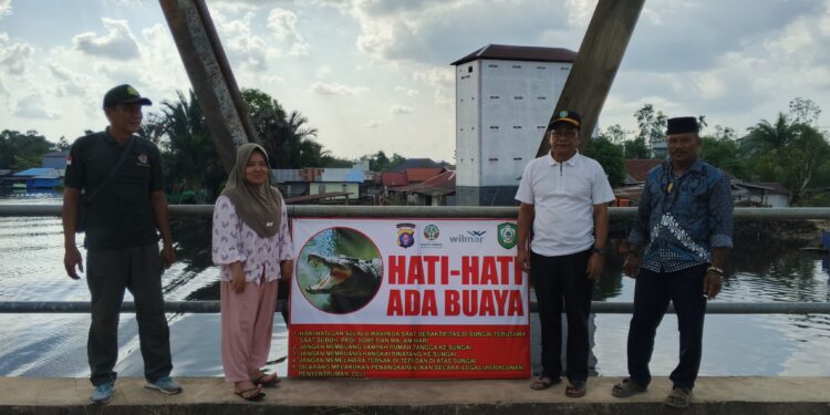 Foto: IST/MATA KALTENG - Anggota DPRD Kotim Eddy Mashamy (baju putih) bersama BKSDA saat pasang spanduk peringatan bahaya kemunculan buaya di Desa Ramban, 4 Mei 2025.