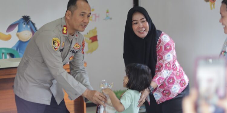 FOTO : HUMAS POLRES GUMAS/MATA KALTENG - Kapolres Gumas AKBP Heri Eko Wibowo didampingi Sekda Richard, memberikan bingkisan dan berinteraksi dengan para anak yang datang ke posyandu Kemala Polsek Kurun, Kamis, 8 Mei 2025.