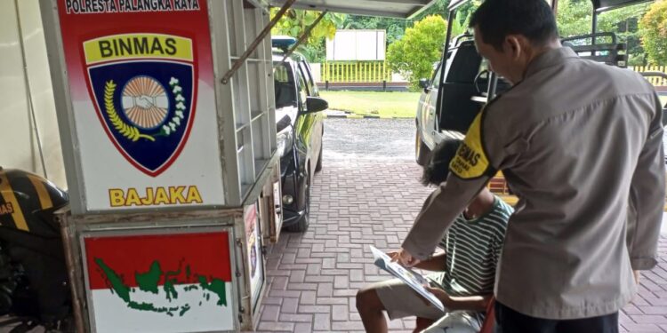FOTO: MATAKALTENG - Personel Polsek Bukit Batu, pada saat membantu warga belajar melalui buku dari Sepeda Motor Bajaka.