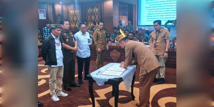 FOTO : DISKOMINFO SANTIK/MATA KALTENG - Bupati Gumas Jaya Samaya Monong menandatangani kesepakatan bersama pengaturan lalu lintas angkutan hasil perkebunan, kehutanan dan pertambangan yang melintasi ruas Jalan Palangka Raya-Kuala Kurun, yang disaksikan Gubernur Kalteng H Agustiar Sabran, di Aula Eka Hapakat, Lantai 3 Kantor Gubernur Kalteng, Selasa, 20 Mei 2025.