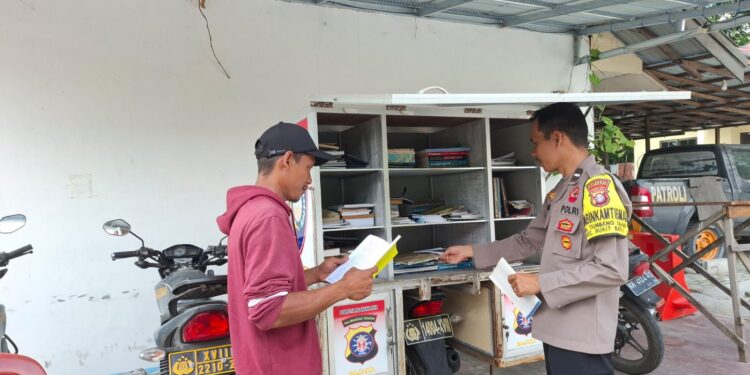 FOTO: MATAKALTENG - Personel Polsek Bukit Batu pada saat memberikan buku bacaan kepada warga.