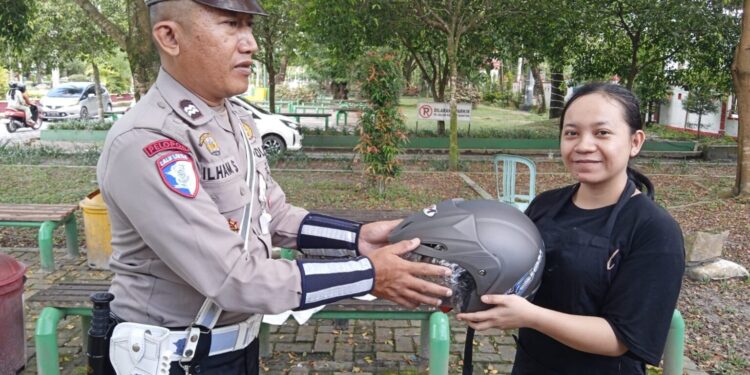 FOTO: MATAKALTENG - Personel Satlantas Polresta Palangka Raya, pada saat menyerahkan helm SNI gratis kepada warga.