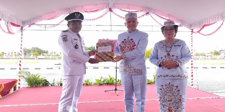 FOTO: SID/MATA KALTENG - Bupati Gumas Jaya Samaya Monong didampingi Wakil Bupati Efrensia LP Umbing, menyerahkan piagam penghargaan kepada Kepala Desa Karya Bhakti Mubarik, pada peringatan Hari Jadi ke 23 Kabupaten Gumas, di halaman kantor bupati setempat, Sabtu 21 Juni 2025.