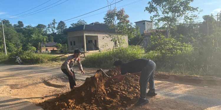 FOTO : POLSEK KAHAYAN HULU UTARA/MATA KALTENG - Personel Polsek Kahayan Hulu Utara bersama warga sekitar menimbun ruas jalan lintas di Kelurahan Tumbang Miri, Kecamatan Kahut, Jumat 27 Juni 2025.