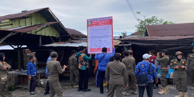 FOTO: DIAN/MATA KALTENG - Pemasangan spanduk pemberitahuan tidak boleh berjualan atau mendirikan Bangunan di atas drainase atau trotoar di Pasar Keramat Sampit, Kamis 17 Juli 2025.