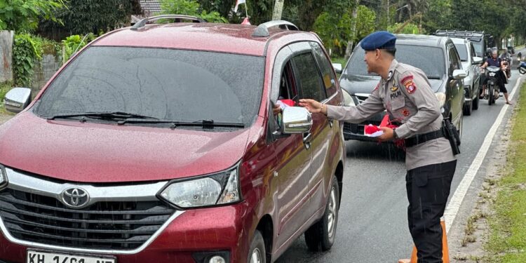 FOTO: MATAKALTENG - Personel Brimob Polda Kalteng pada saat membagikan bendera kepada pengguna jalan.